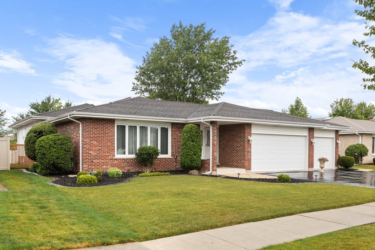 Suburban home with brick siding, three car garage and neat landscaping